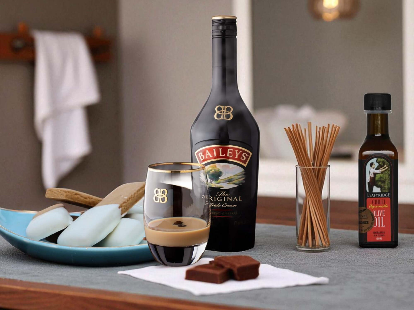 Baileys bottle with a glass of coffee and chocolate on a table.