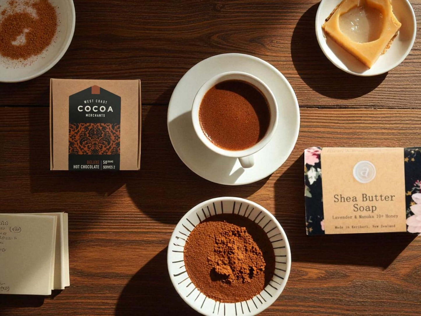 Cocoa powder, a cup of cocoa, and soap bars on a wooden table
