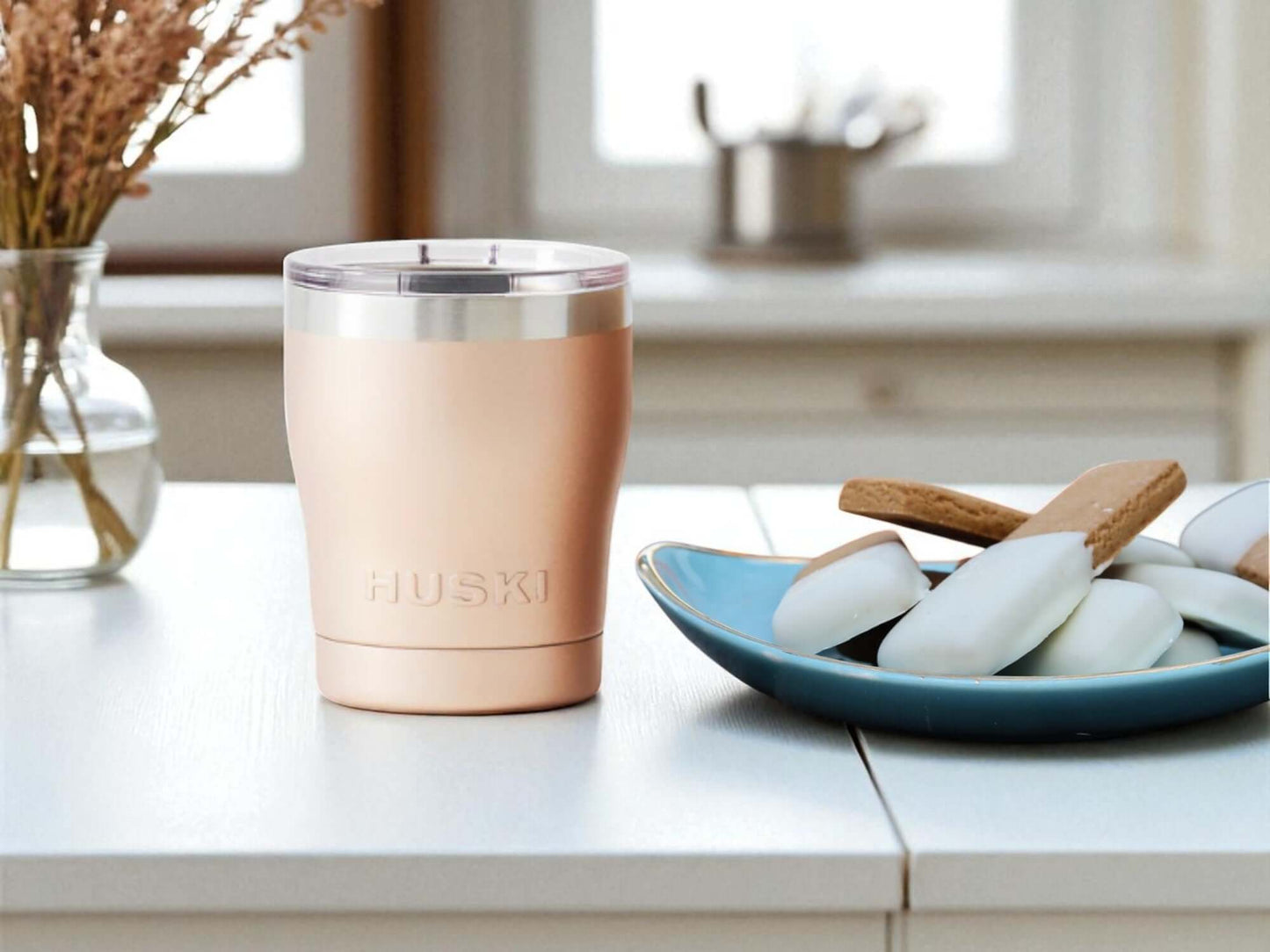 Rose gold tumbler with 'HUSKI' branding on a kitchen counter.