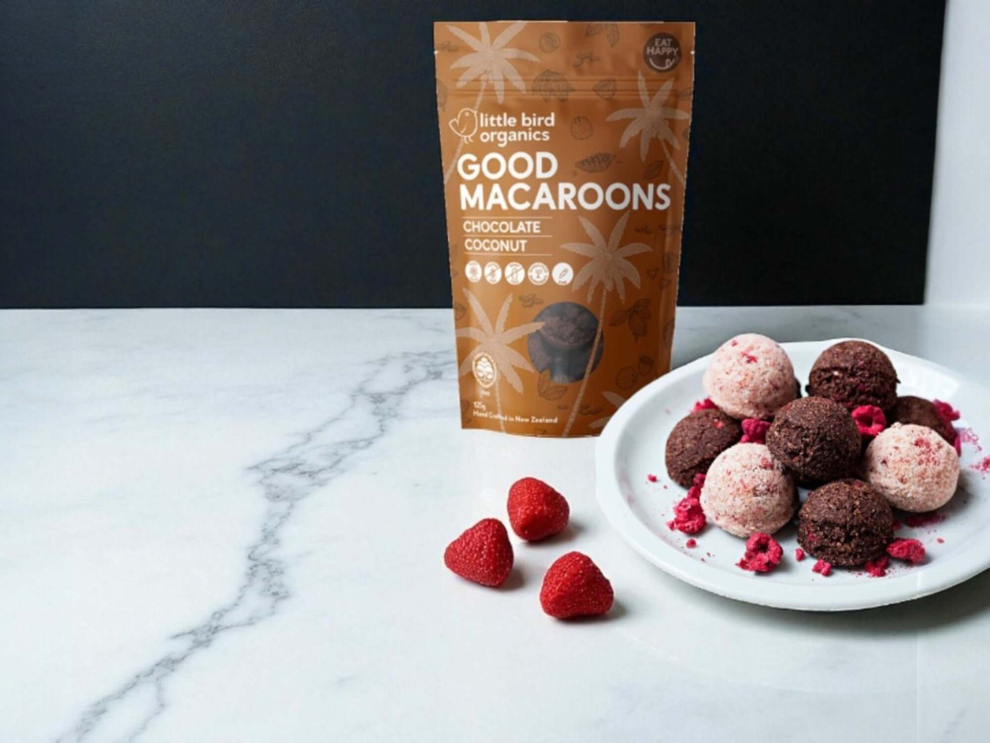 Plate of macaroons with a package labeled 'Good Macaroons' on a marble surface.