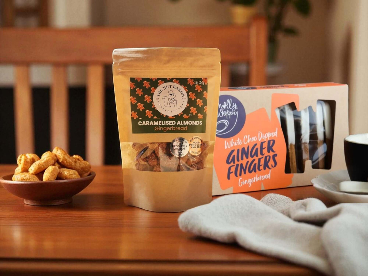 Table with a bowl of nuts, a bag of caramalised almonds, and a box of ginger fingers.