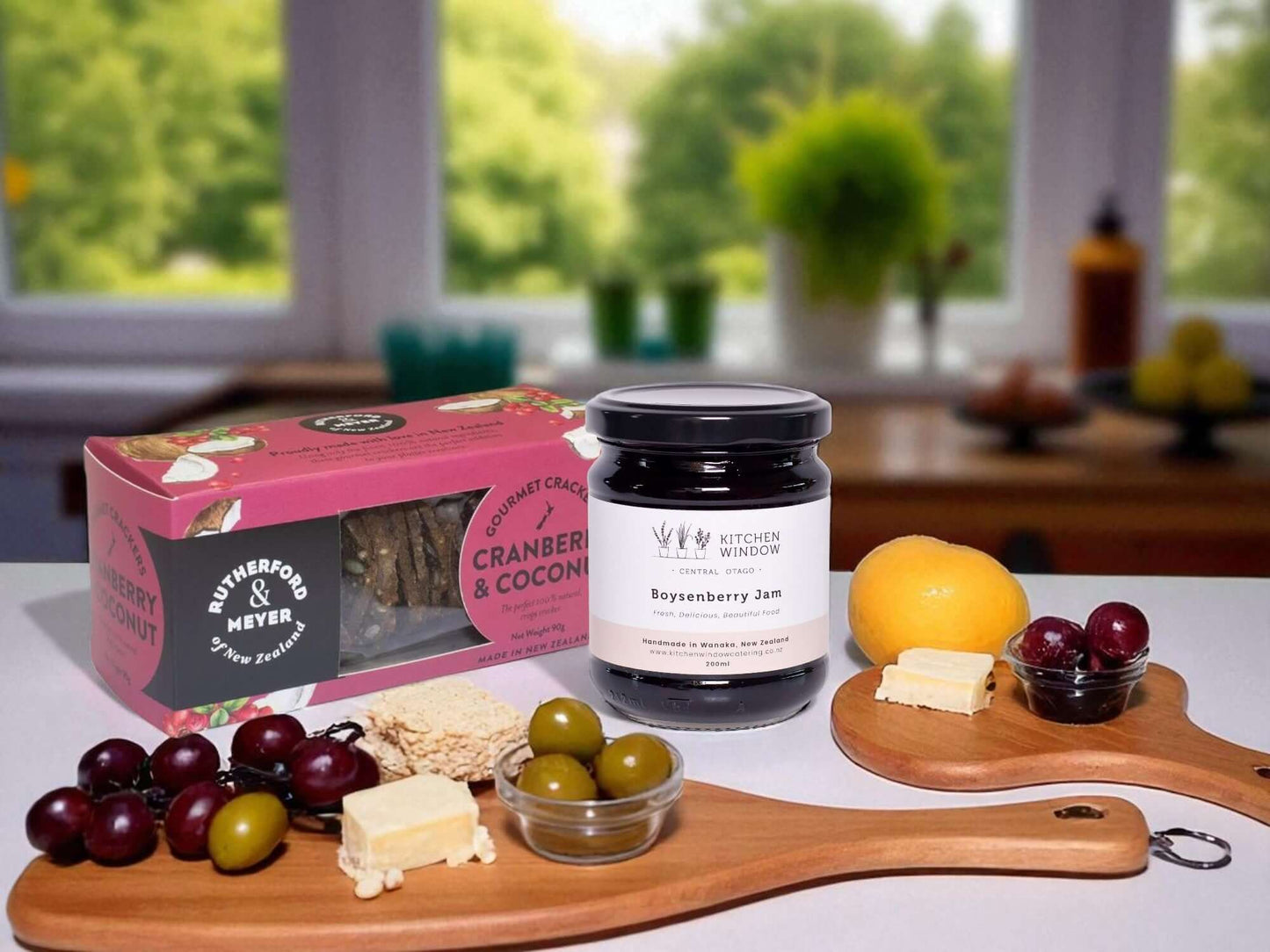 Assorted food items including a jar of jam, crackers, and fruits on a table with a blurred background.