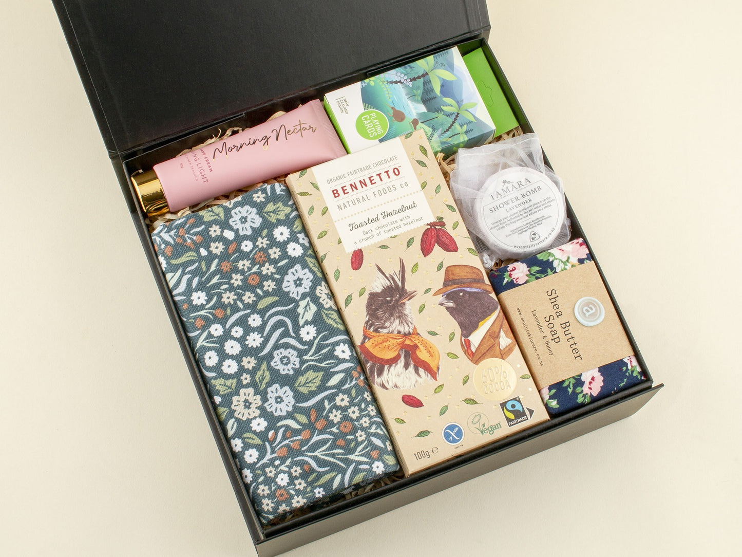 Gift set with various products including a bar of soap, a tea bag, and a small container on a beige background.