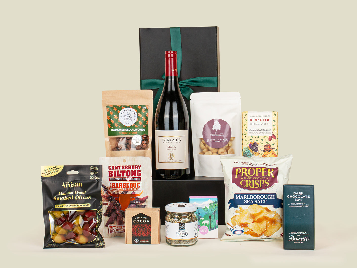 Assorted gourmet food items including a bottle of wine, snacks, and small containers on a light background