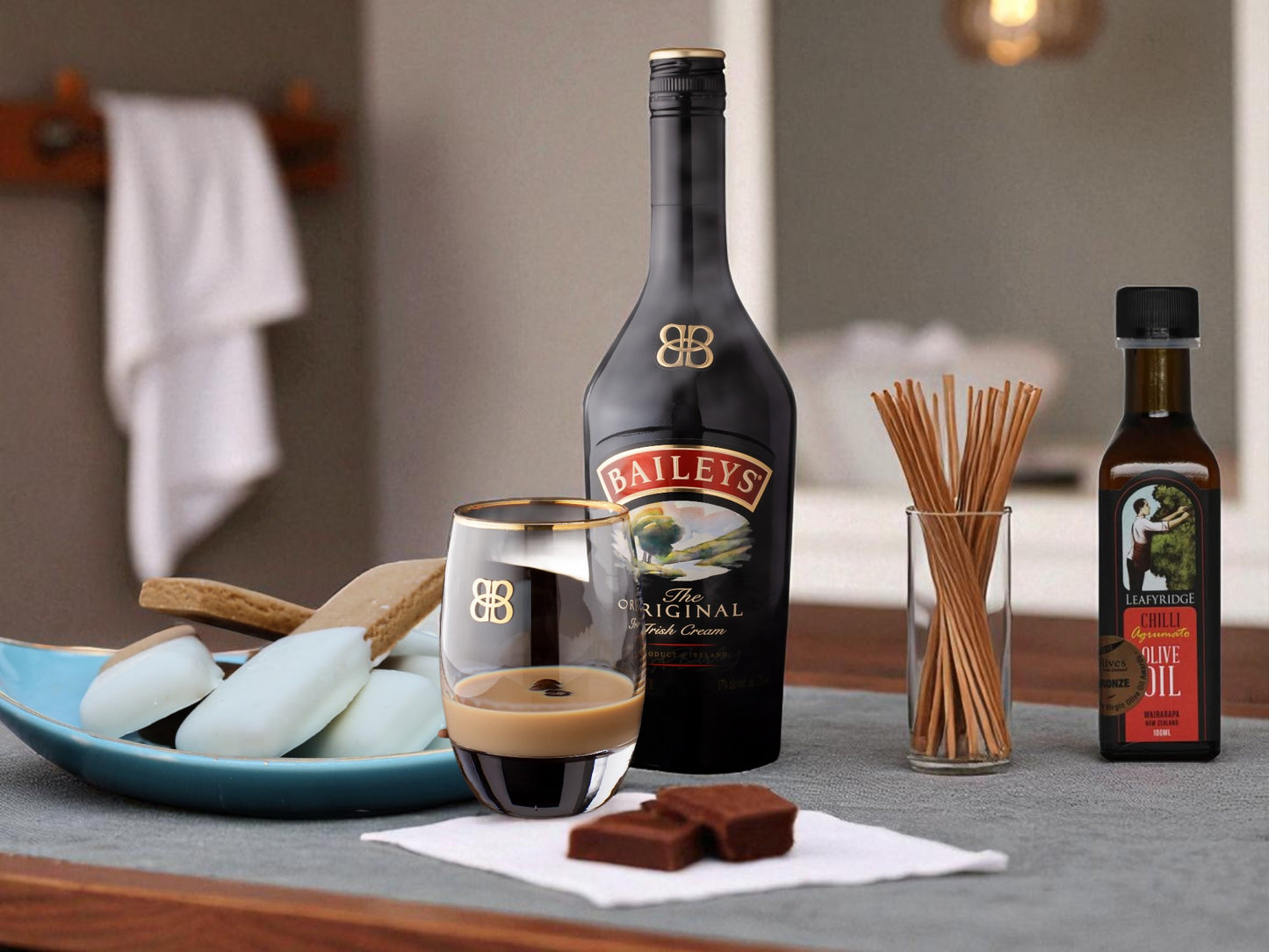 Baileys bottle with a glass of coffee and chocolate on a table.