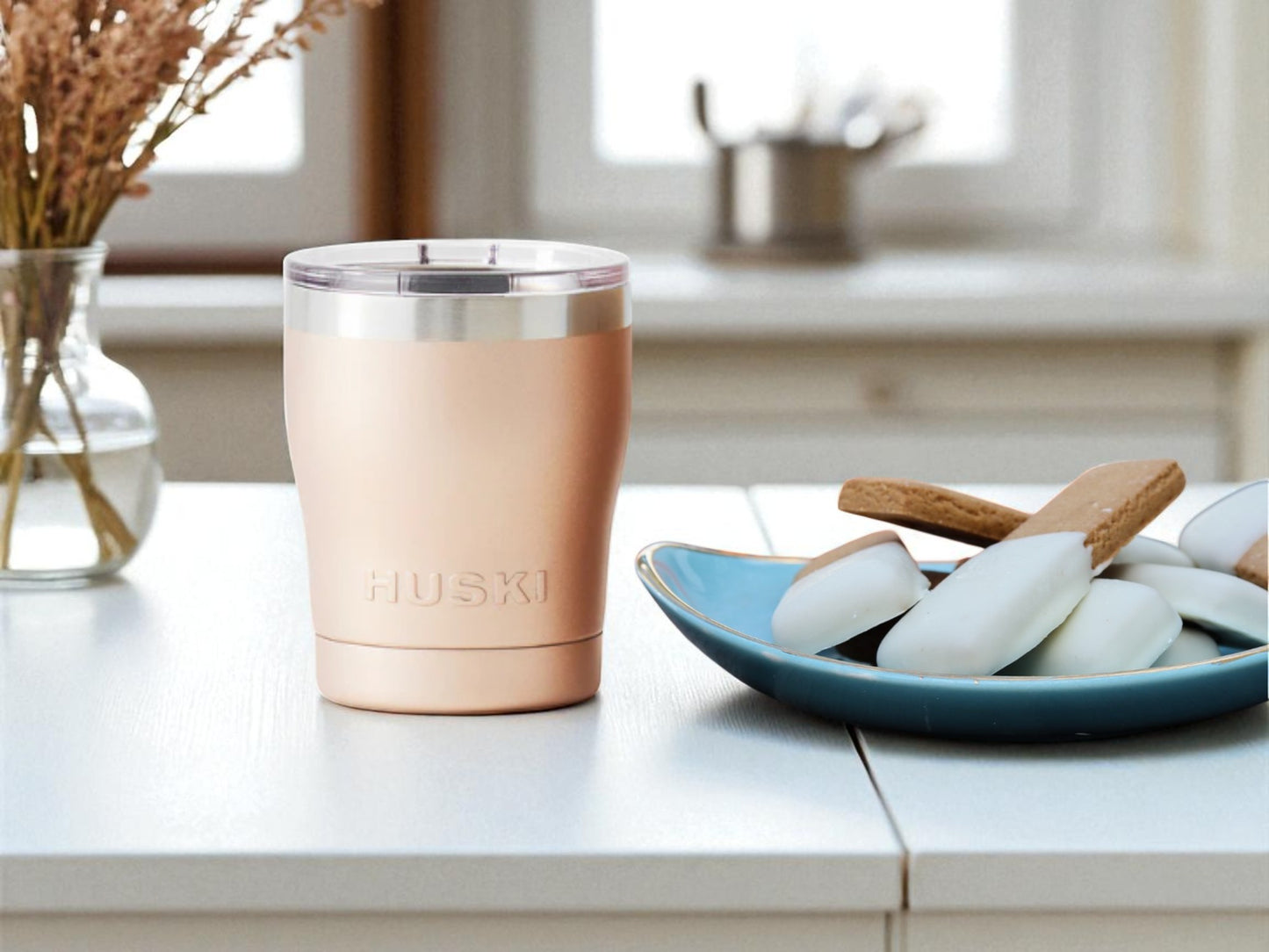 Rose gold tumbler with 'HUSKI' branding on a kitchen counter.