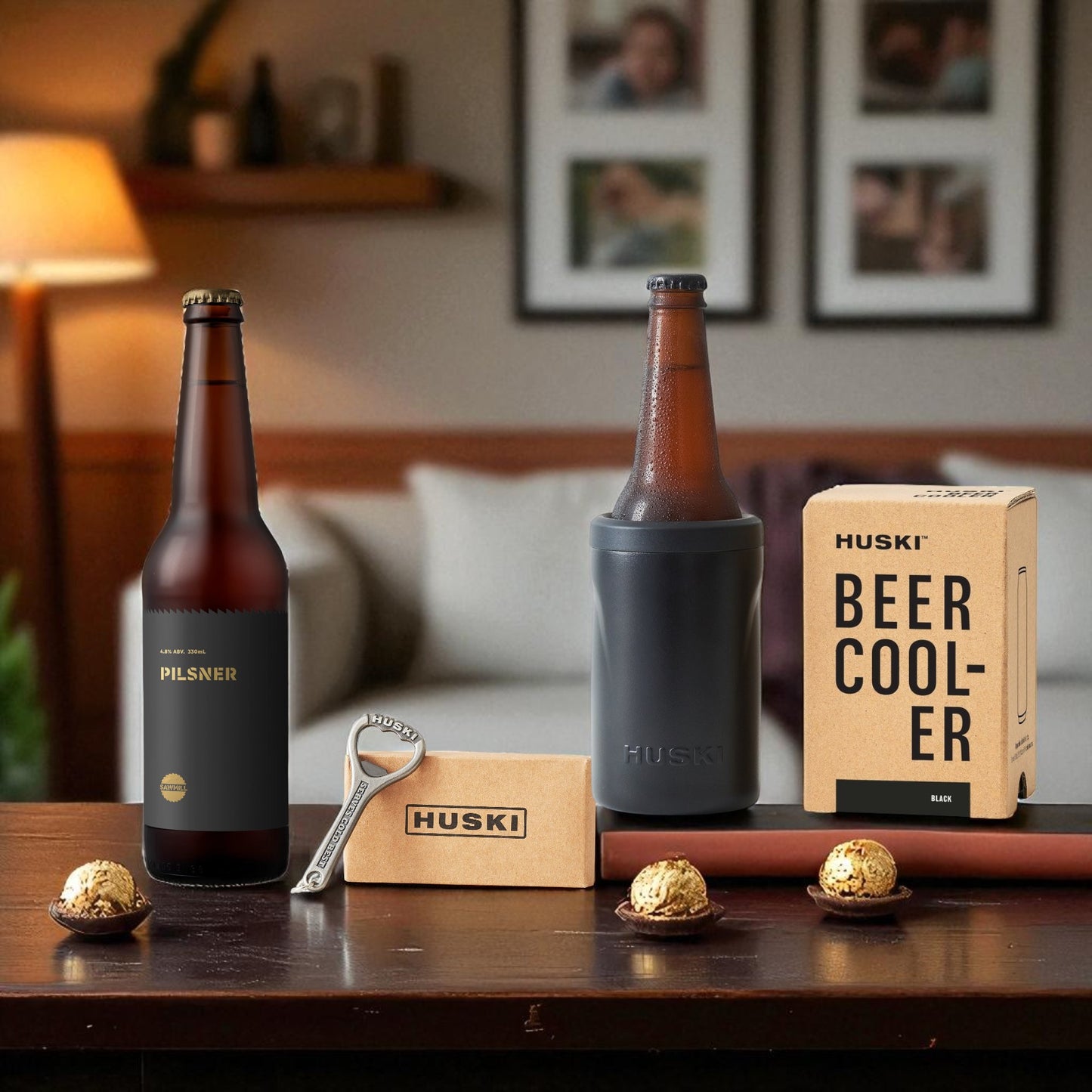 Two bottles of beer, a beer cooler, and a bottle opener on a wooden table with a blurred background.