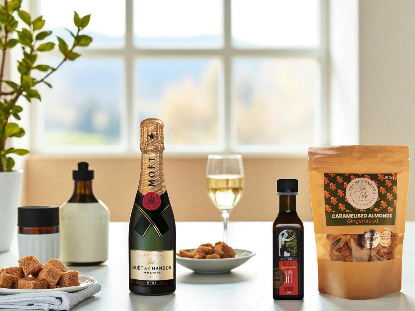 Table with champagne bottle, snacks, and other items in a bright room.