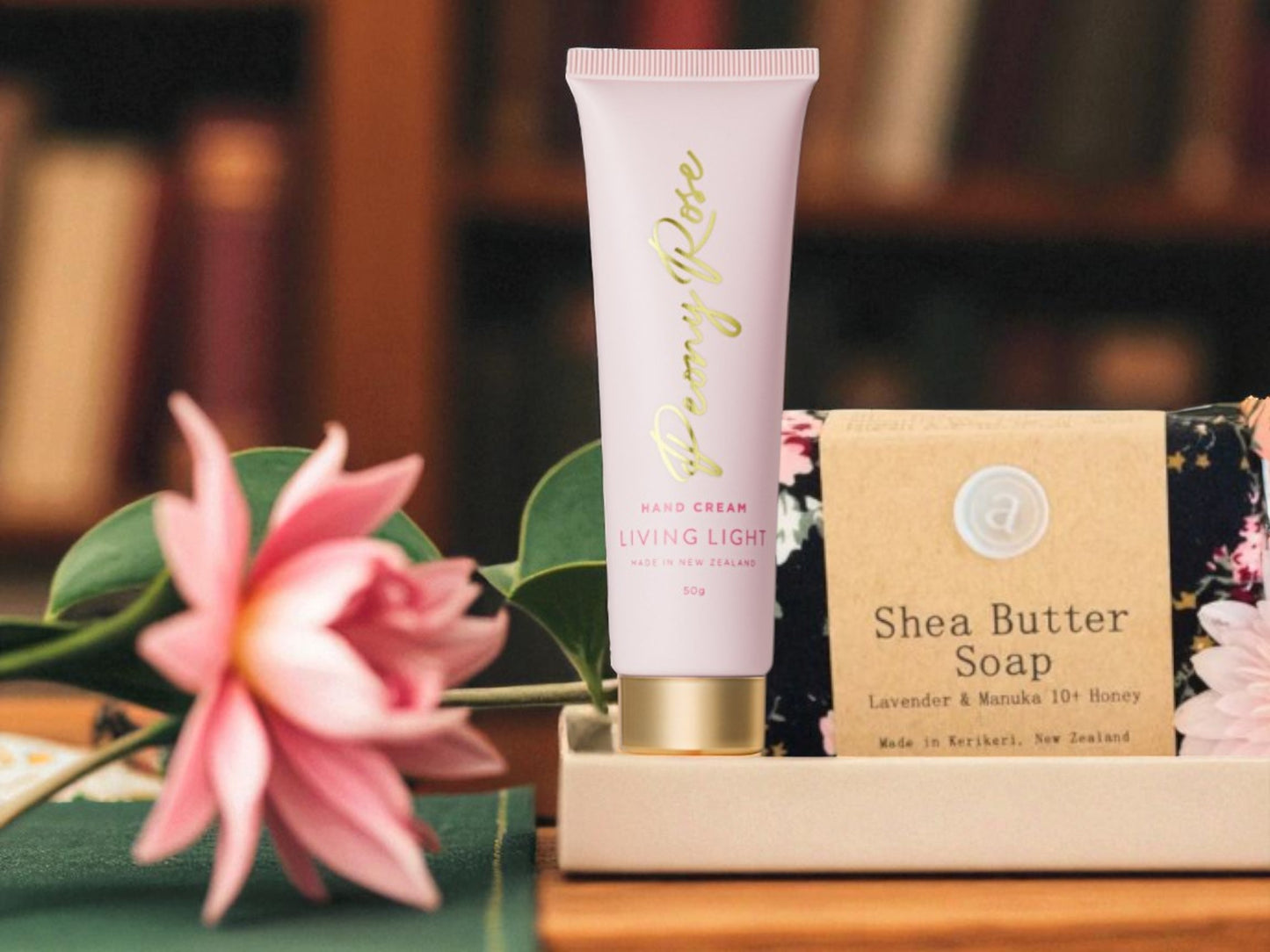 Shea butter soap and body cream with a pink flower on a wooden surface